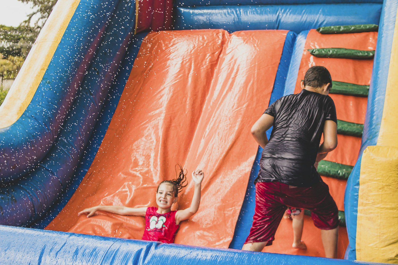 Children playing on a wet inflatable slide.