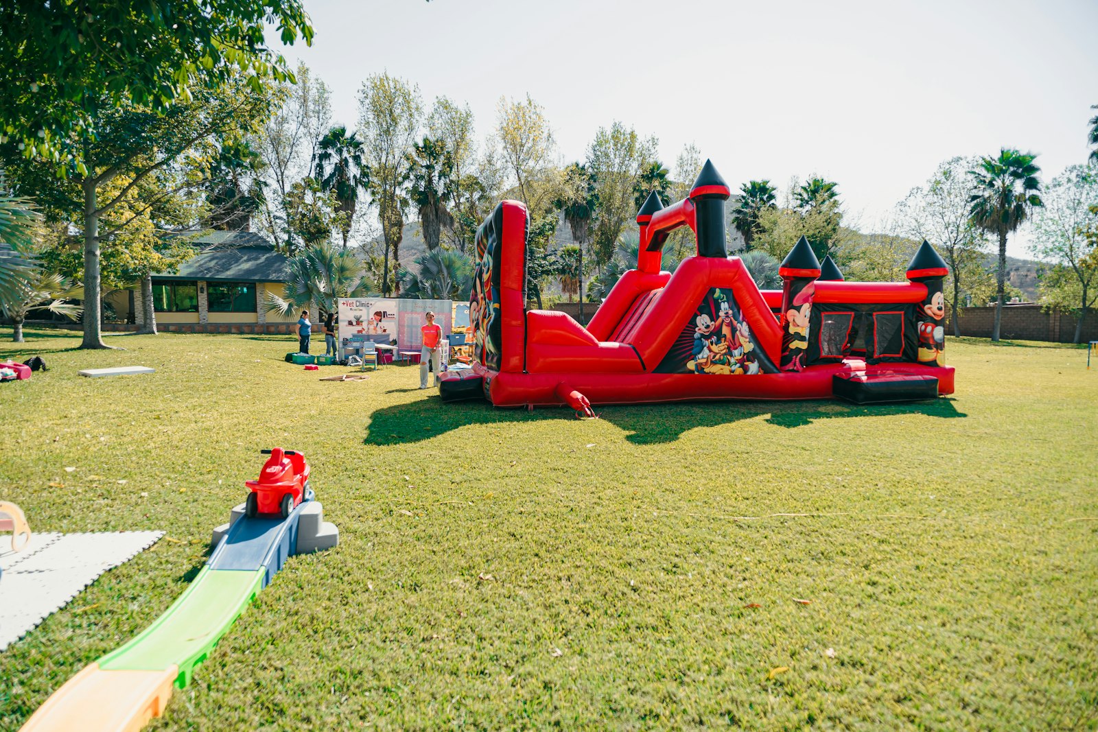 A large red inflatable bounce house with a slide on a grassy field.