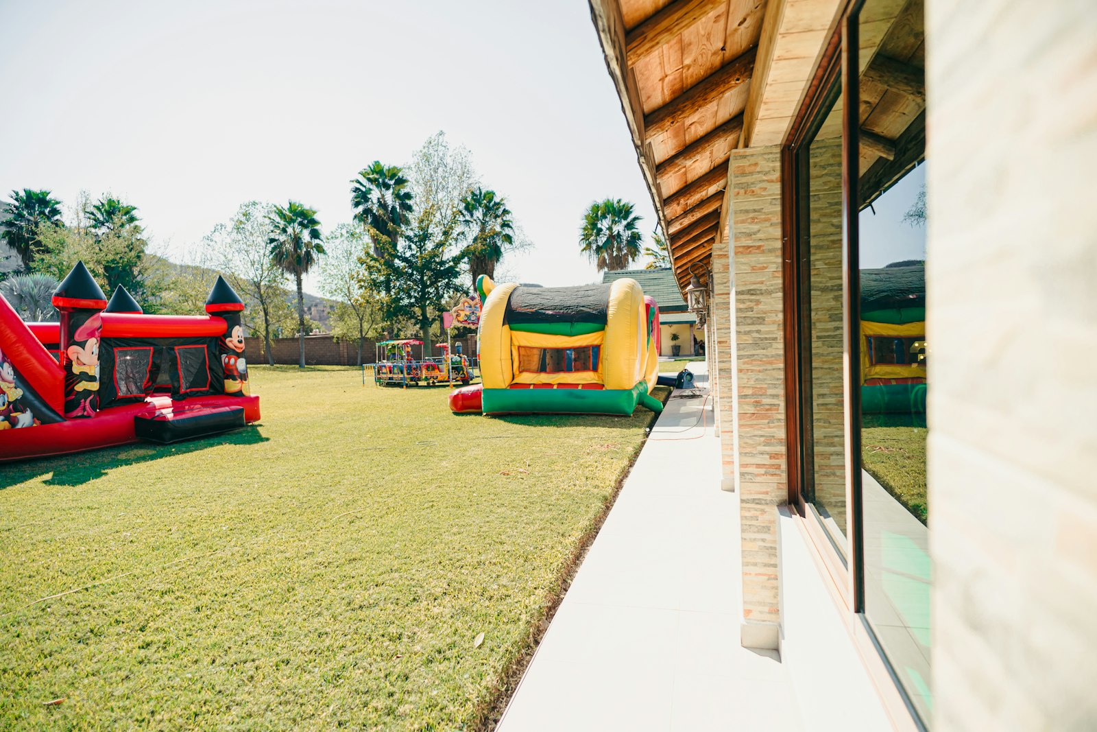 Two inflatable bounce houses set up on a grassy lawn next to a house.